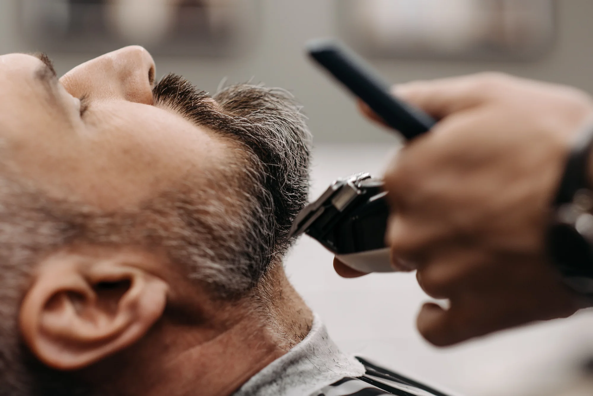 Close-up demonstration image of clippers shaping a beard line.